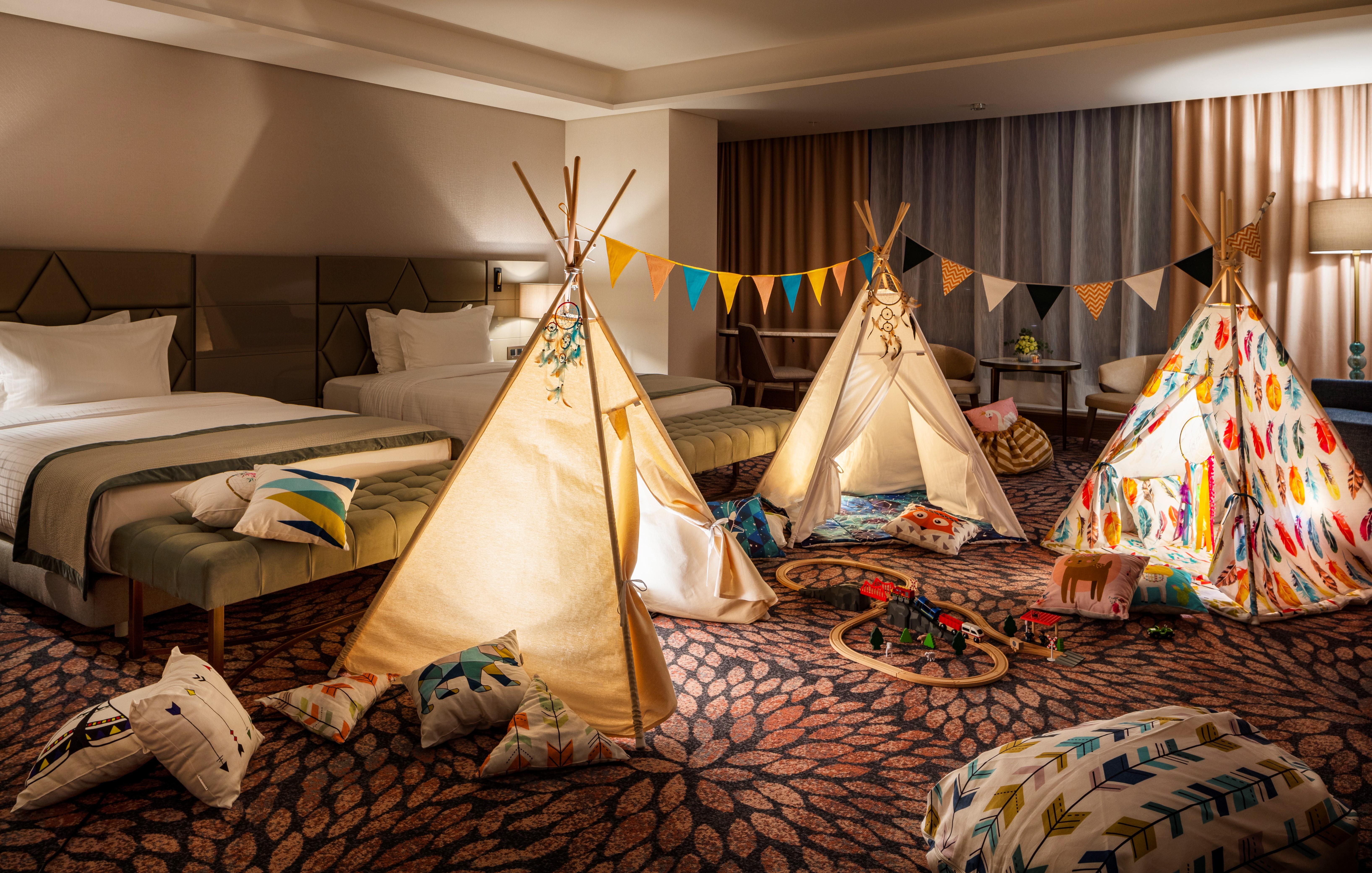 Grand Hotel Millennium 索菲亞 外观 照片 The photo shows a cozy room featuring three children's teepees made of fabric, arranged in a playful manner. The teepees are decorated with colorful patterns and surrounded by various cushions and pillows scattered on the floor. There are also decora